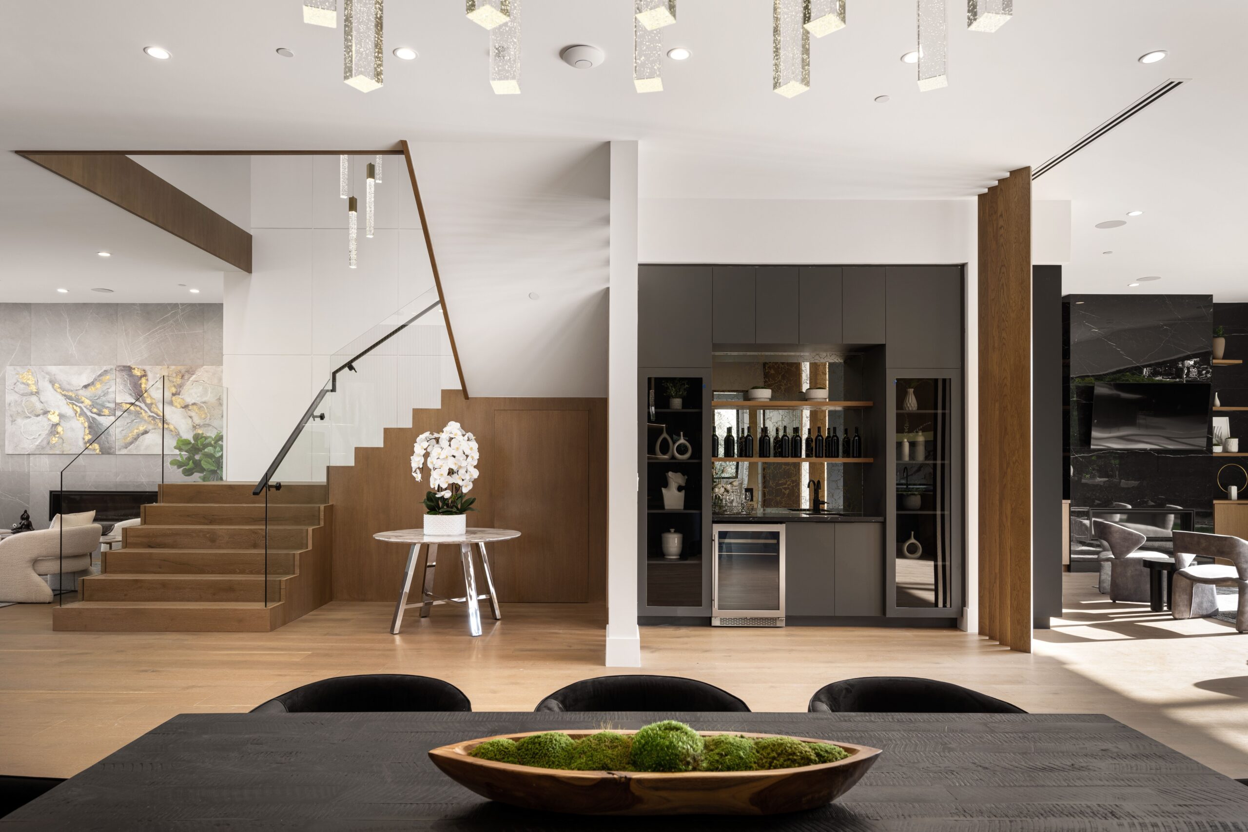 Modern interior of a luxury home featuring a stylish staircase, open kitchen, and elegant decor with natural light.